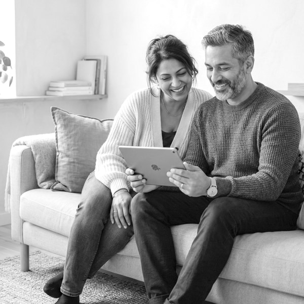 Ouders zitten op de bank achter een tablet.